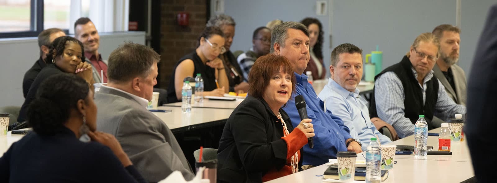 Professional development conference with several adults and one speaking into a microphone