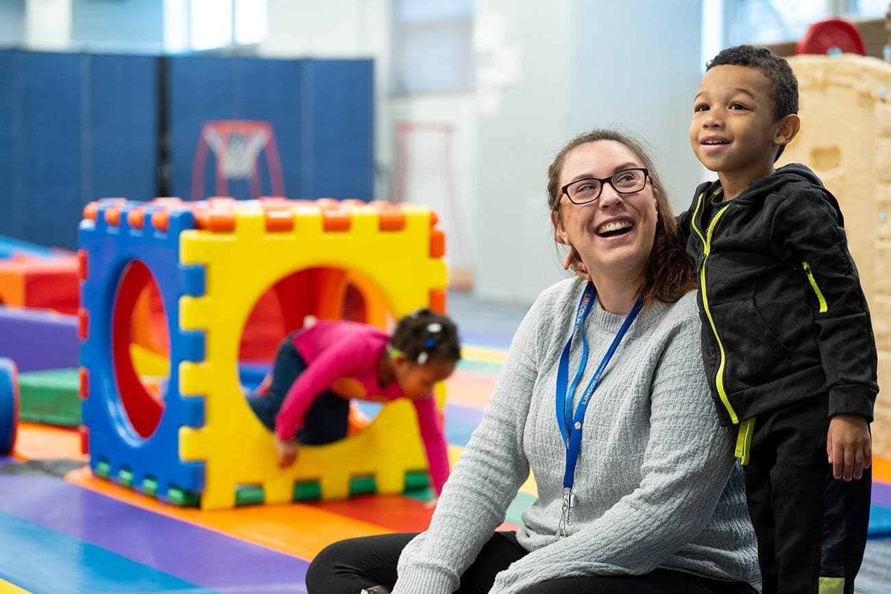 Teacher smiling next to student at a play session during school